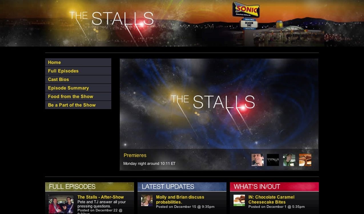 The finished Stalls homepage: a wide starfield header with 'THE STALLS' in thin serif caps and a Sonic drive-in glowing at dusk on the right, a left nav (Home, Full Episodes, Cast Bios, Episode Summary, Food from the Show, Be a Part of the Show), a trailer pane over a blue nebula, and a three-column grid of Full Episodes, Latest Updates, and What's In/Out.