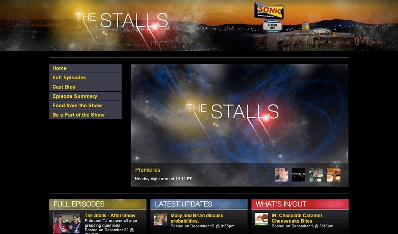 The finished Stalls homepage: a wide starfield header with 'THE STALLS' in thin serif caps and a Sonic drive-in glowing at dusk on the right, a left nav (Home, Full Episodes, Cast Bios, Episode Summary, Food from the Show, Be a Part of the Show), a trailer pane over a blue nebula, and a three-column grid of Full Episodes, Latest Updates, and What's In/Out.